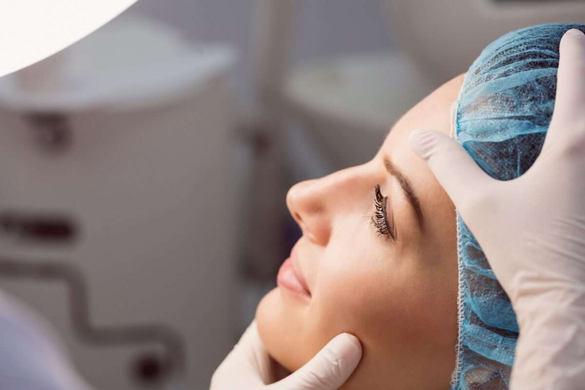 Hands of doctor examining womans face for cosmetic treatment at clinic Hands of doctor examining womans face for cosmetic treatment at clinic
